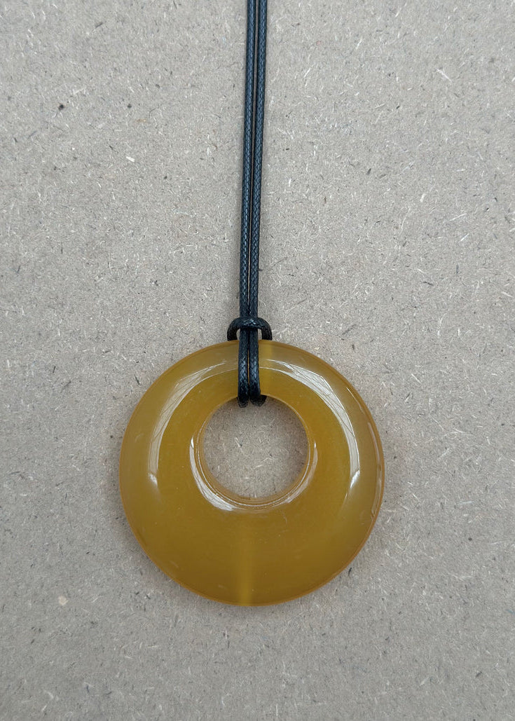 Round amber-colored pendant on a gray background