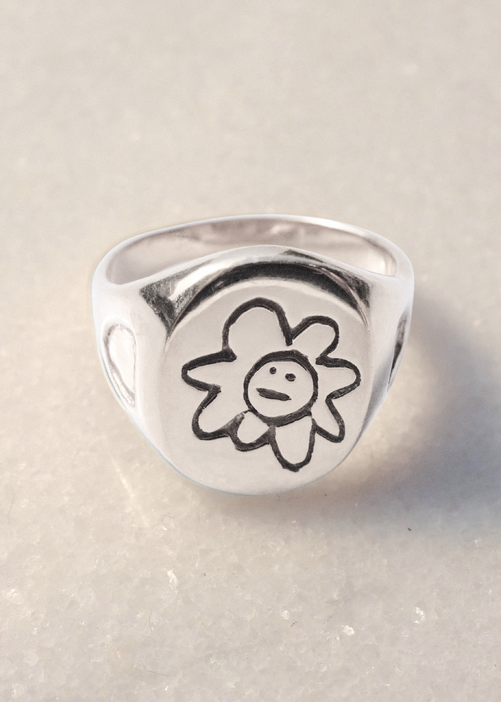 Silver ring with a flower design on a light background
